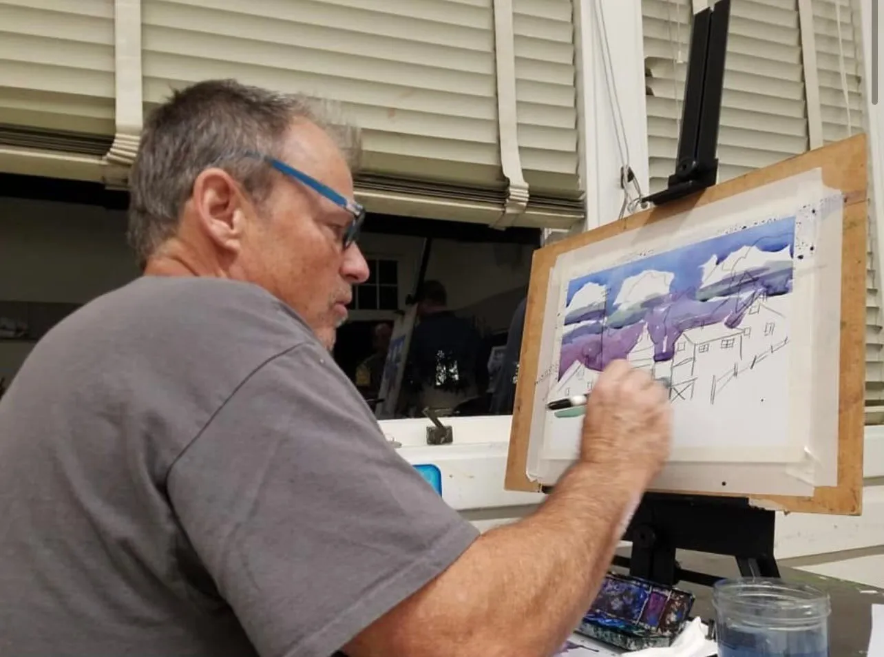 Wade Norman painting a watercolor at his easel, brush in hand